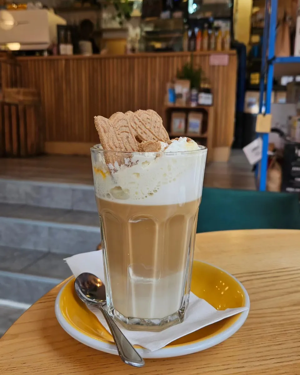 Pumpkin Spice Latte im Glas mit Schlagsahne und Keks